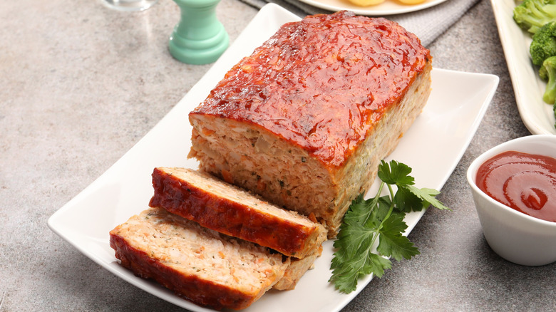 Meatloaf on a white plate with parsley and vegetables
