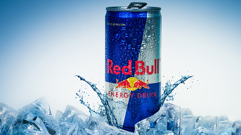 A can of Red Bull set on top of ice on a blue background