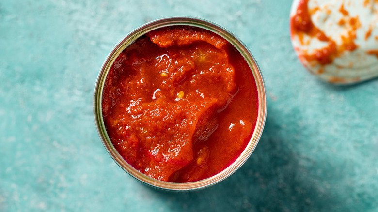 An opened can of tomato sauce on a blue background.