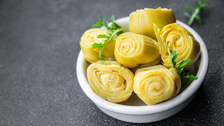 White bowl full of canned artichoke hearts