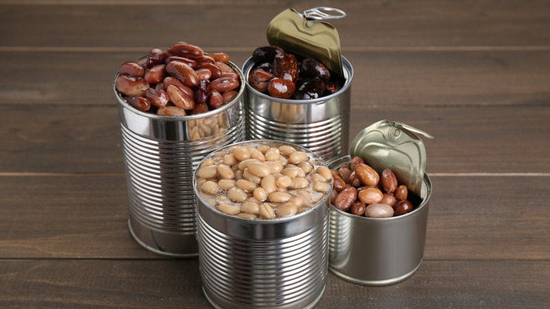 Opened tins of beans on a wooden surface