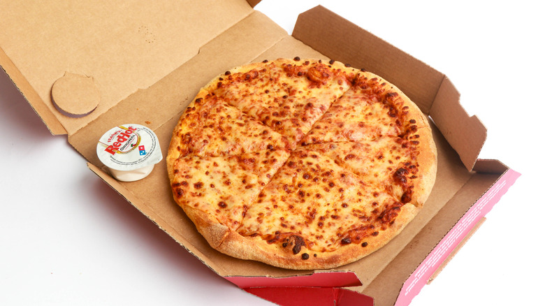 Open box of Domino's cheese pizza with Red Hot dip
