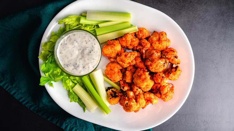 buffalo cauliflower served on a white platter with dipping sauce