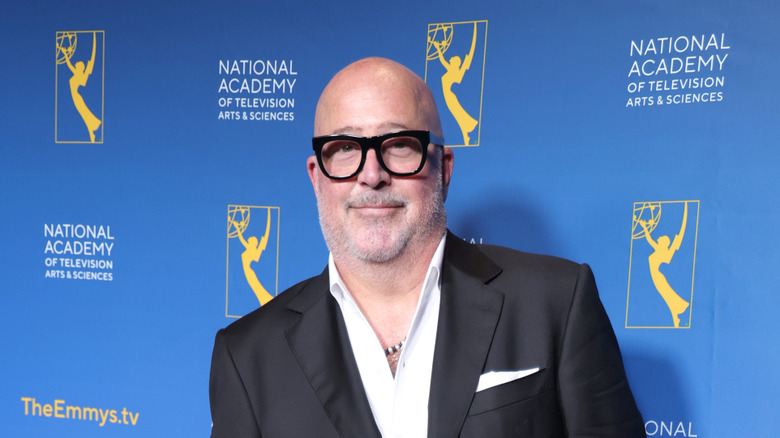 Andrew Zimmern wearing a suit and posing for a photo at an awards show