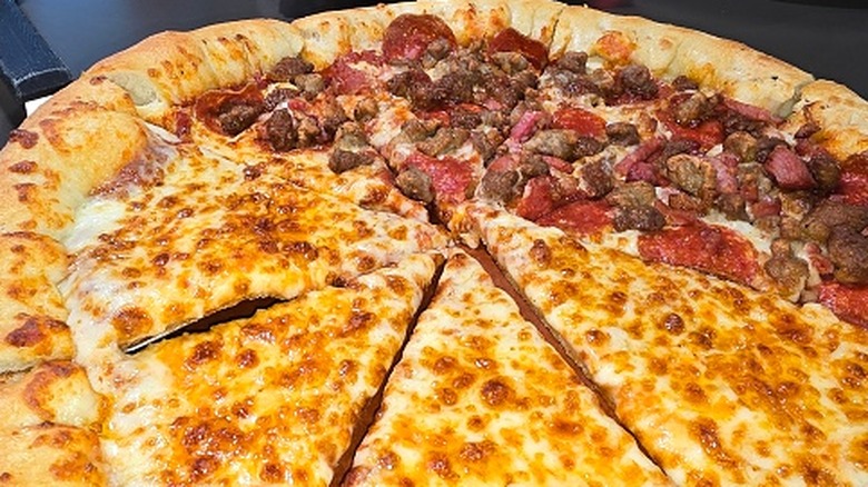 An extra large pizza is topped with meat