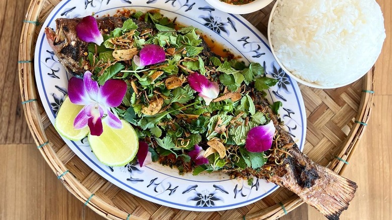 A whole fried fish with greens and flower petals from Hai Hai in Minneapolis