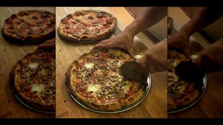 Pizza being sliced at Apizza Scholls
