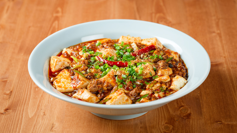 White bowl of mapo tofu on a wooden table