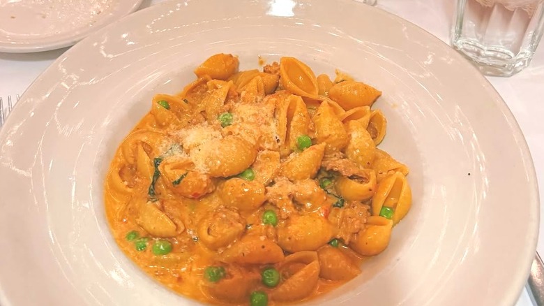 Topo Gigio's conchiglie alla sarda, which is a tomato-based dish with green peas, served on a white plate.