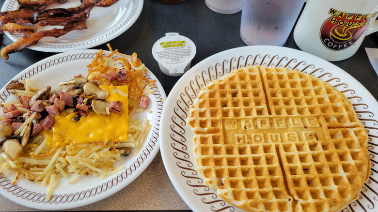 Breakfast dishes from Waffle House including bacon, waffles, and cheesy hash browns