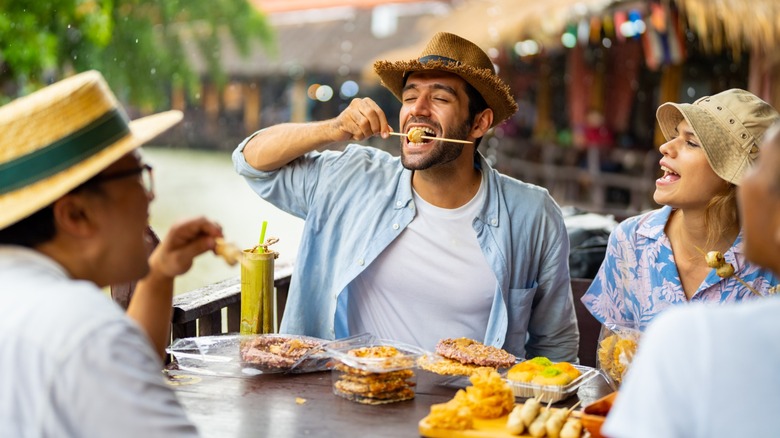 tourists eating food together at a black table