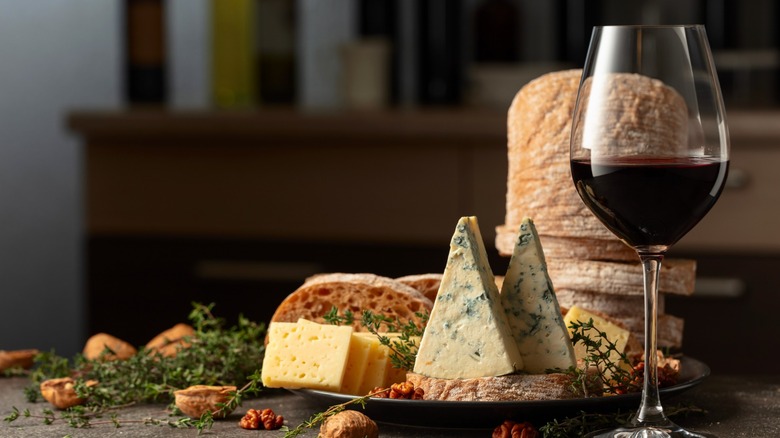glass of wine with an assortment of cheeses and breads