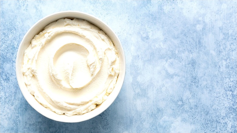 Creamy bowl of ricotta cheese on blue and white background