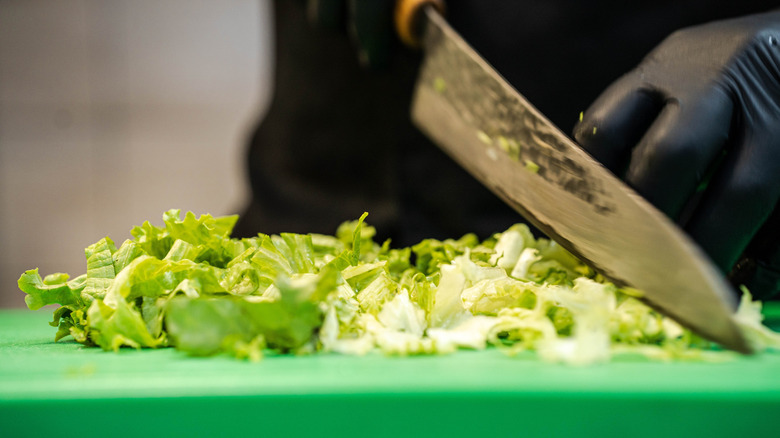lettuce being chopped on green cutting board
