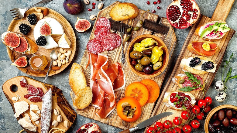 Charcuterie spread with sliced salami, prosciutto, blackberries, figs, and crostini