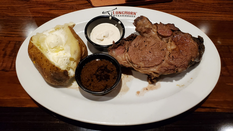 Longhorn Steakhouse branded plate with prime rib, condiments, and a baked potato