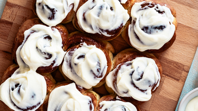 Cinnamon rolls on cutting board topped with icing