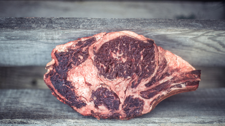 A dry-aged porterhouse steak on a wooden board.