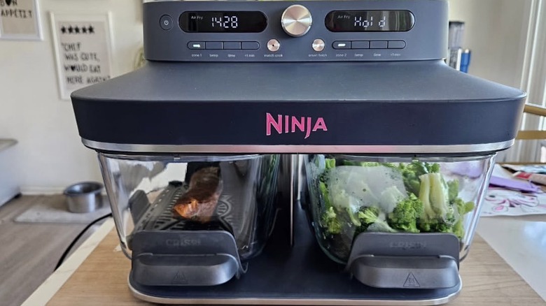 a glass airfryer filled with meat and veggies on a kitchen counter