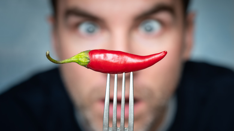 Person looking at a chili pepper on a fork
