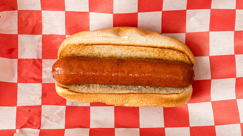 Hot dog in a bun over checkered red and white paper