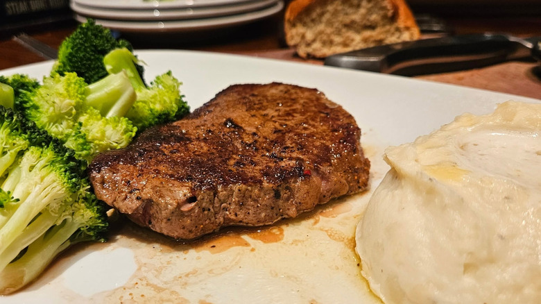A filet mignon with broccoli and mashed potatoes on a white plate at Longhorn Steakhouse