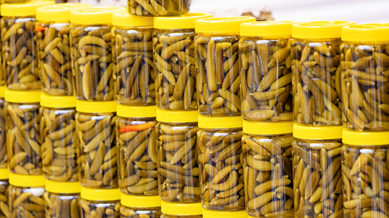 Numerous jars filled with pickled cucumbers.