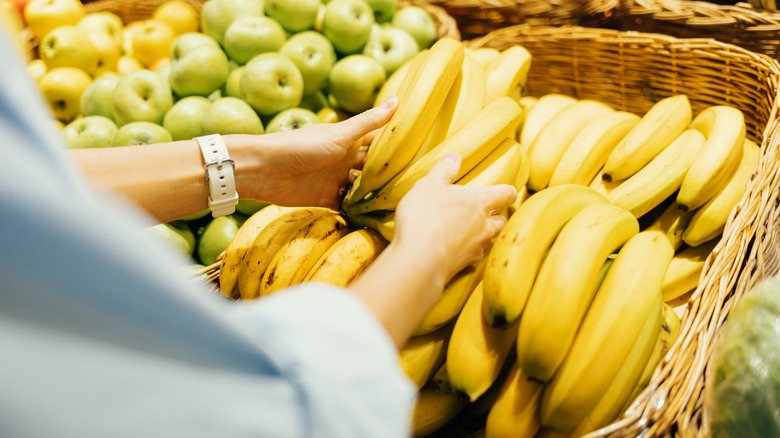 Customer touches a bunch of bananas at the supermarket.