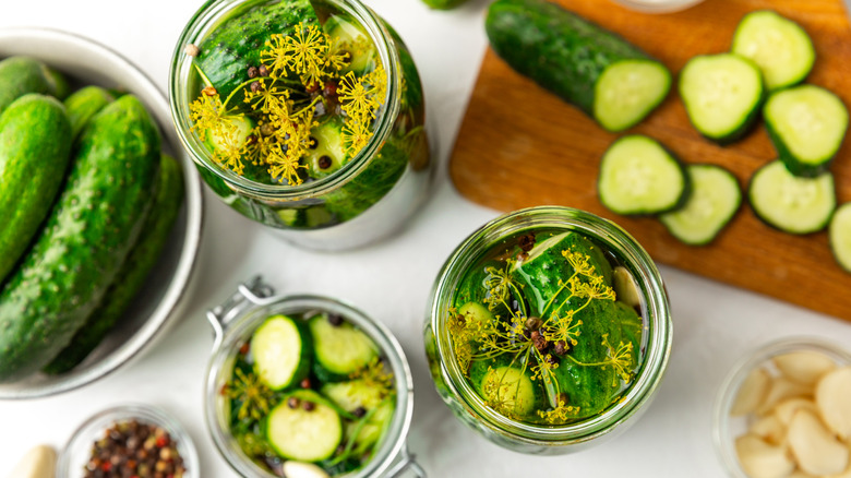 Variety of cucumbers in a bowl, on a cutting board, and in pickling jars