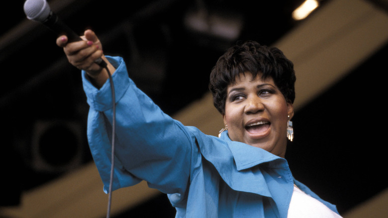 Aretha Franklin smiling and holding out a microphone
