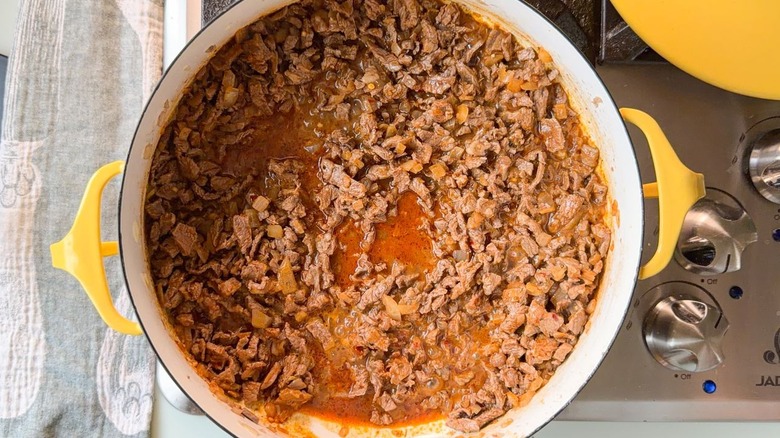 Picadillo beef simmering in yellow pot on stovetop