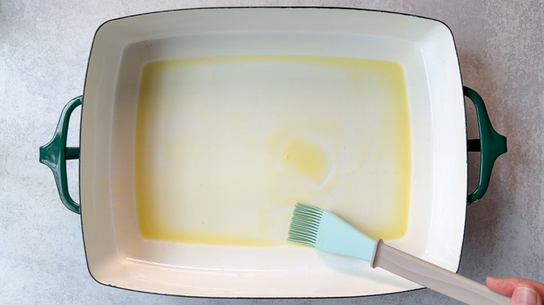 Brushing olive oil inside a 13 x 9 baking dish