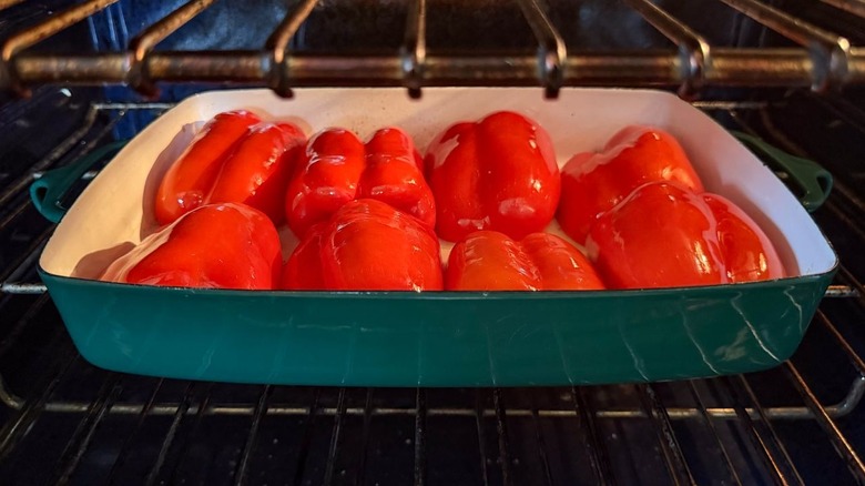 Red bell pepper halves roasting in oven in baking dish