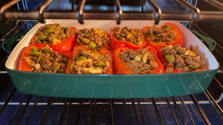 Argentinian picadillo beef-stuffed red bell peppers in baking dish in oven