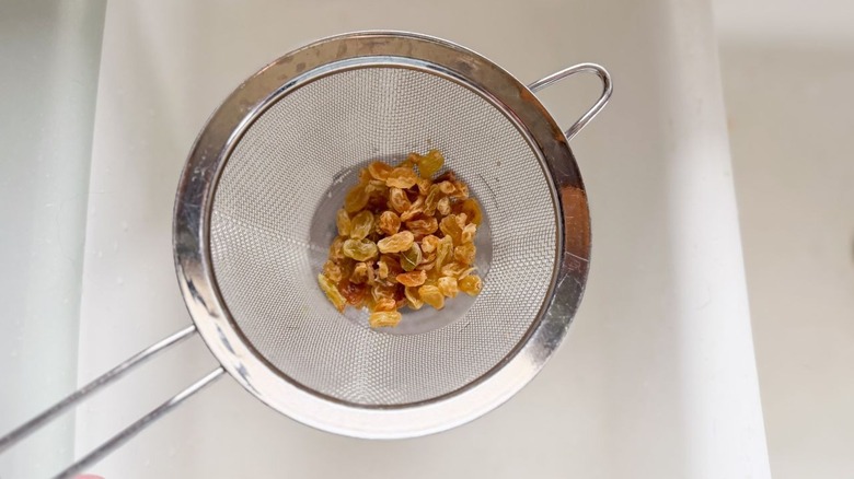 Golden raisins in mesh strainer over sink