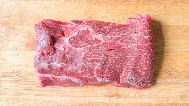 Partially frozen flatiron steak on cutting board