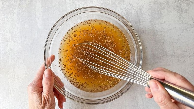 Whisking brine for aromatic smothered smothered pork chops in glass bowl