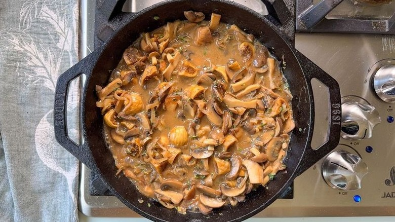 Aromatic smothered pork chops sauce simmering in cast iron skillet on stovetop