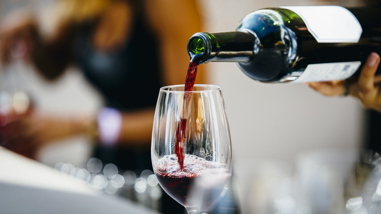A man pouring red wine into a wine glass.