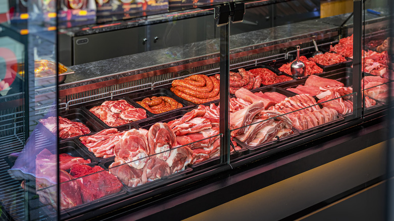 Many meat varieties are on display in a butcher's case.