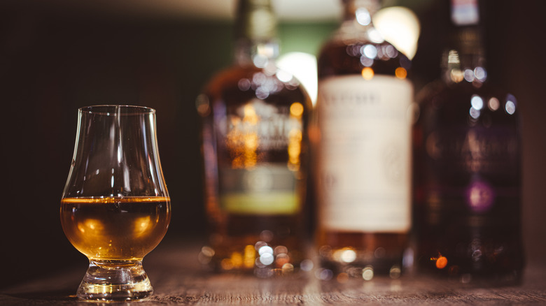 bourbon glass with bottles in the background