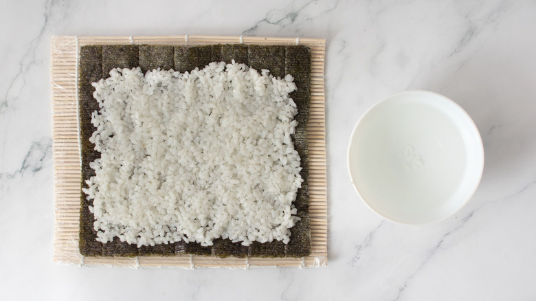 Nori sheet with rice next to small bowl