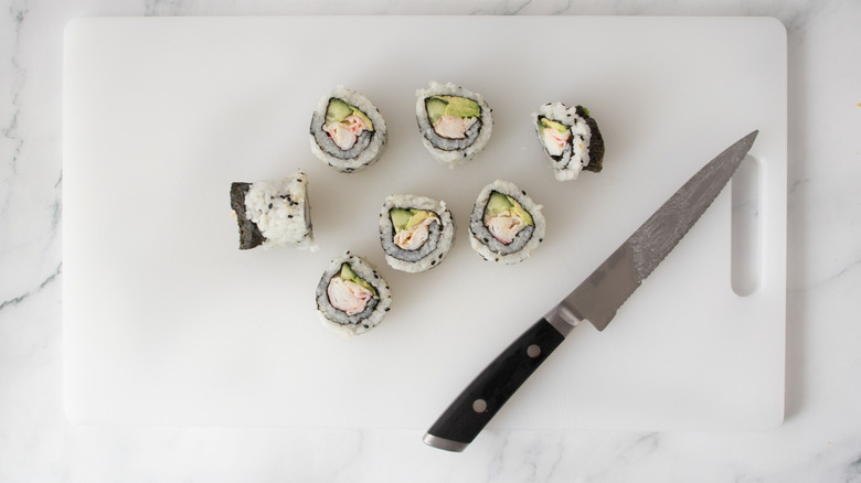 Sliced sushi on cutting board with knife