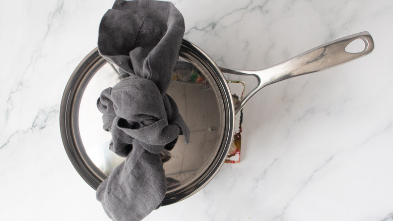 Saucepan with lid and kitchen towel twisted on top