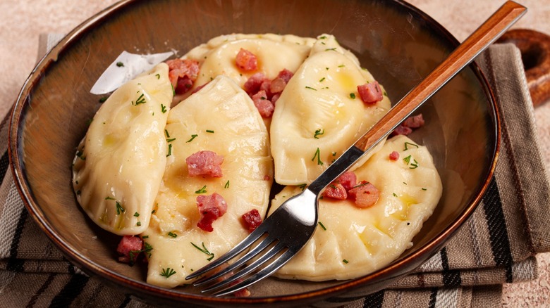 Bowl of buttered pierogi with fork