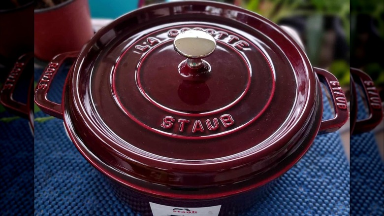 New maroon Staub Dutch oven on a blue tablecloth