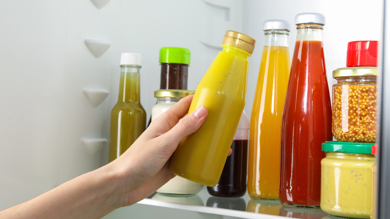 woman taking a bottle of mustard out of the fridge