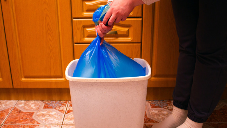 A person takes a trash bag out of trash can