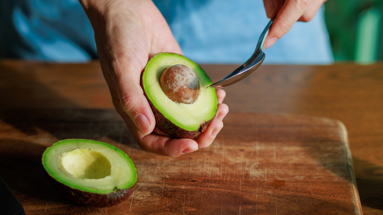 A woman peeling an avocado.