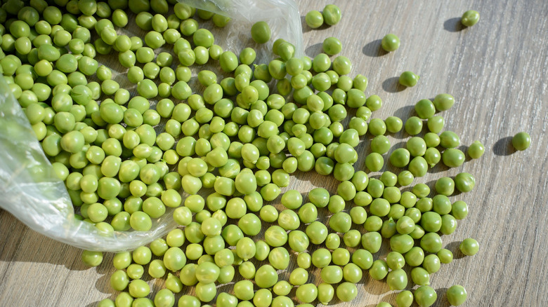 Peas spilling from plastic bag onto table